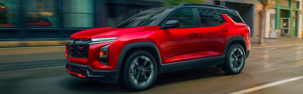 Red Chevy Equinox driving on city street, side view.