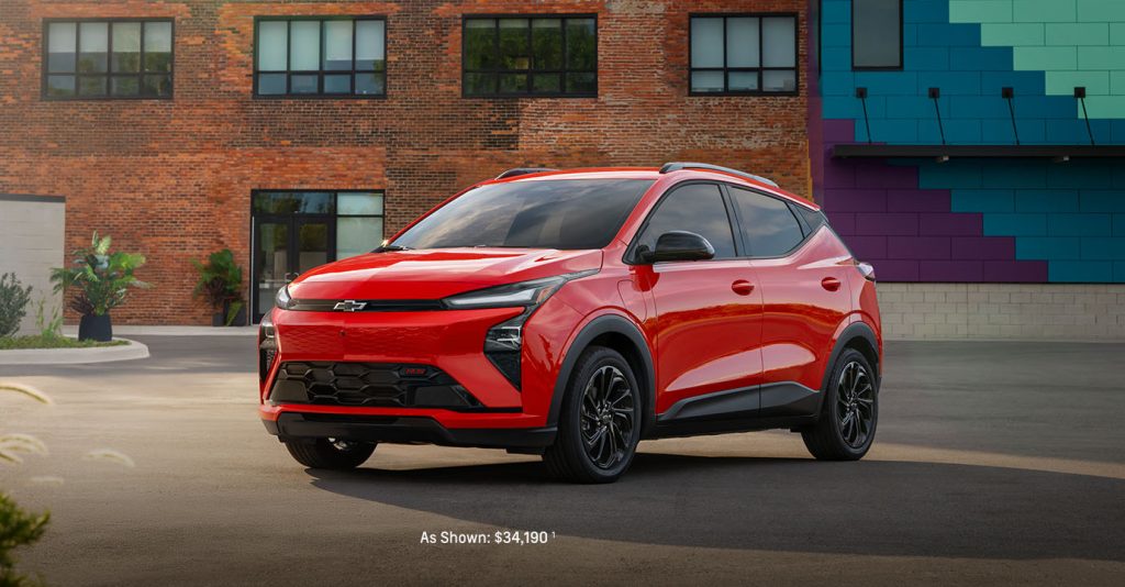 Red Chevrolet SUV parked in an urban setting in front of a brick building with colorful wall panels.