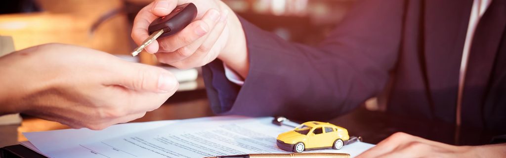 Car finance paperwork with vehicle key handover at a dealership.