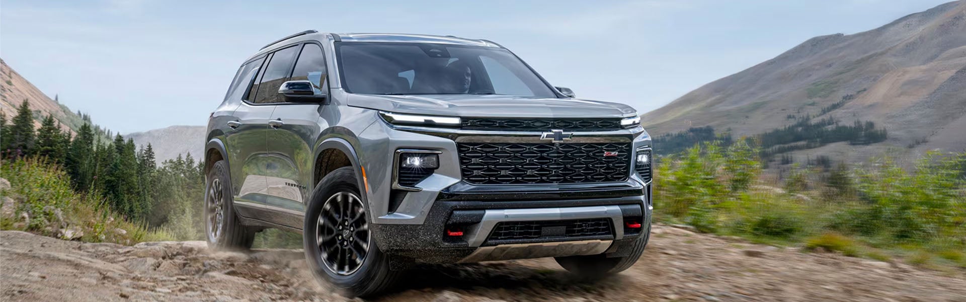 Silver Chevrolet SUV driving on an off-road trail.